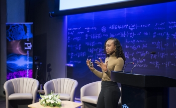 Black woman physicist presenting her work in front of an audience at Perimeter Institute's Inspiring Future Women in Science event in 2018