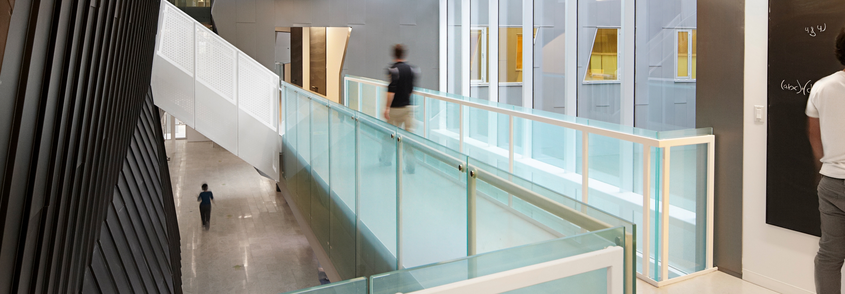 Person walking down an open hallway surrounded by glass windows