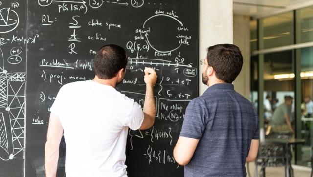 Two men working together on a blackboard