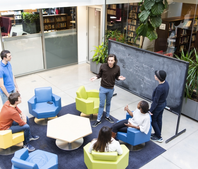 PSI students interacting in front of a blackboard in the atrium