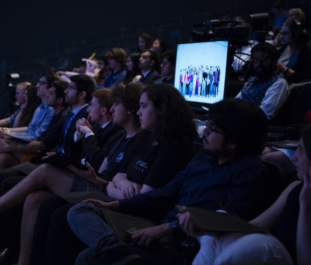 Group of students in a theatre listening to a presentation