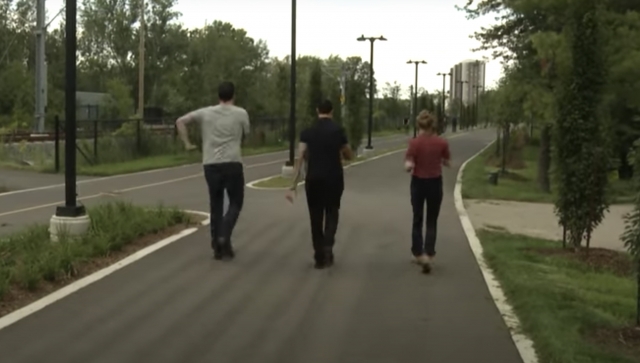 Two men and a woman walking on a path in a park