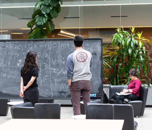Man and women working at blackboard together in atrium