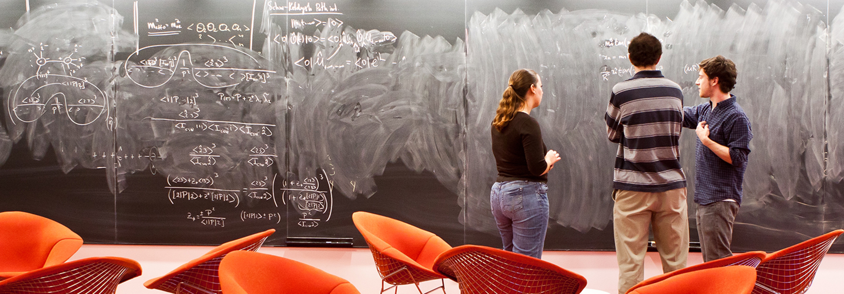three researchers discussing in front of a blackboard in the sky room